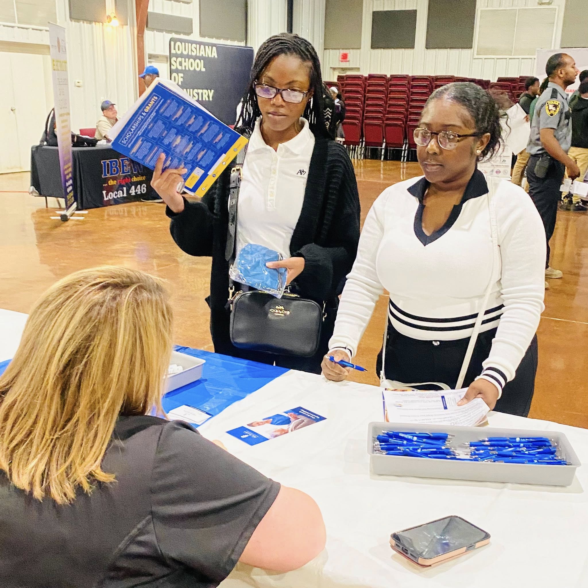 A woman sitting at a table talking to two teen girls.